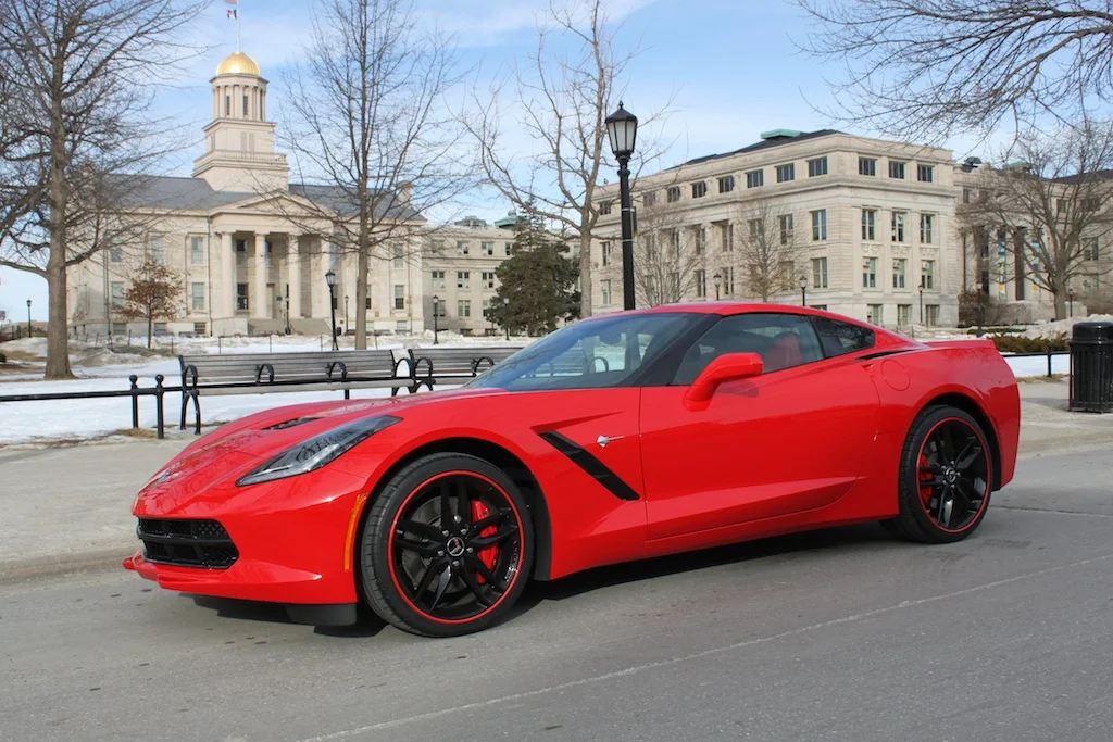 A sleek red sports car parked in front of a historical building with a golden dome.