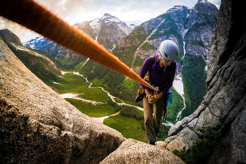 woman climbing rocks using climbing rope